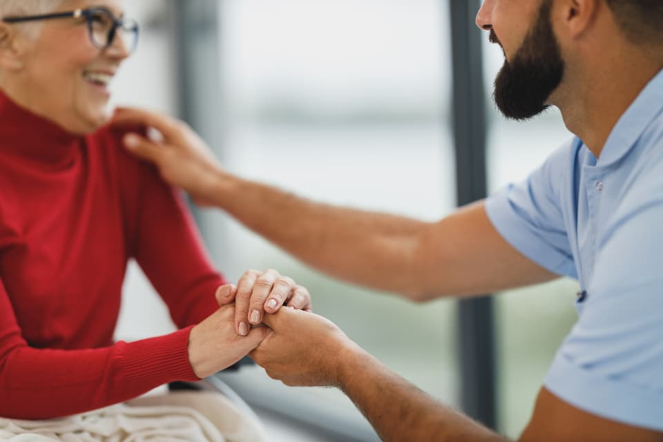 A carer holding an elderly woman's hands