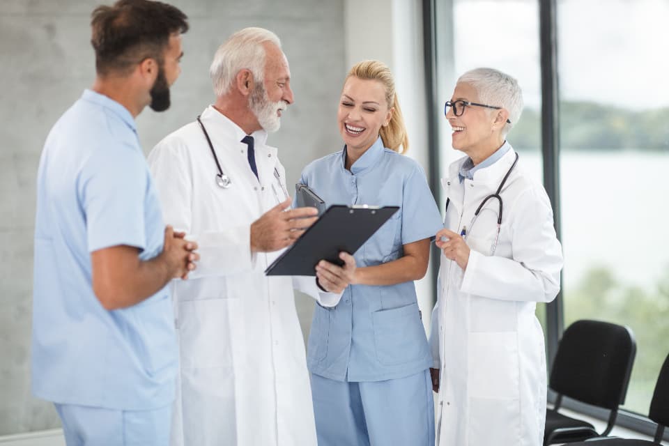 Four clinicians discussing a case together by a window