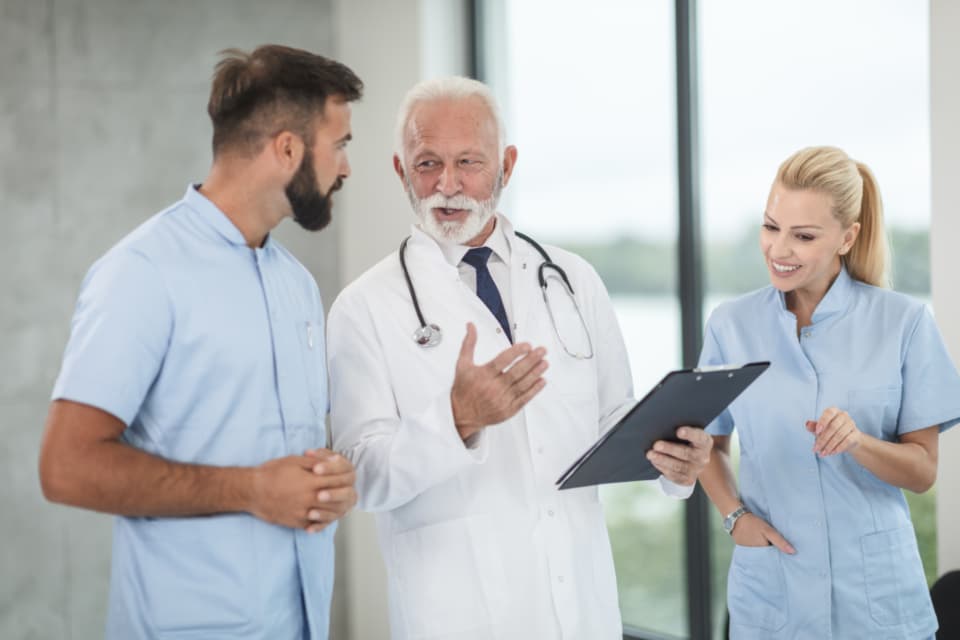 A nurse, doctor and colleagues chatting by a window